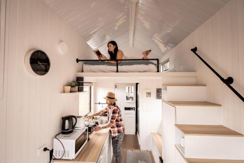 a man standing in the kitchen of a tiny house at Odyssean Tiny House B by Tiny Away in Cessnock