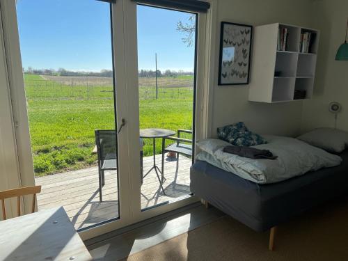 Ein Zimmer mit einer Tür zu einer Terrasse mit Tisch und Stuhl in der Unterkunft Almegården in Græsted