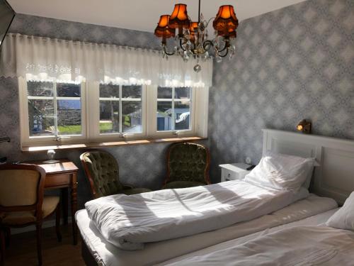 a bedroom with a bed and a desk and windows at Kastanjelund in Yngsjö