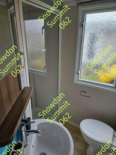 a bathroom with a toilet and a sink and a window at Snowdon Summit 062 in Barmouth