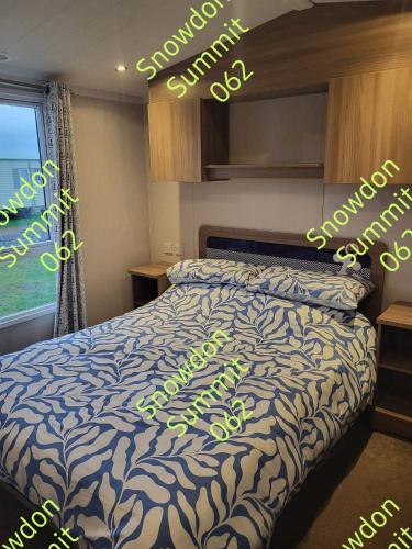 a bedroom with a bed with a blue and white comforter at Snowdon Summit 062 in Barmouth