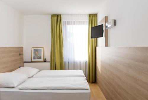 ミュンヘンにあるホテル アムバのベッドとテレビが備わるホテルルームです。