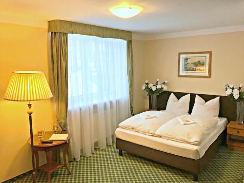 a bedroom with a bed and a lamp and a window at Pensjonat BELVEDERE in Szczyrk