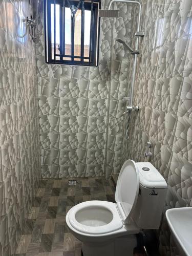 a bathroom with a toilet and a window and a sink at Gekamo Suites in Dar es Salaam