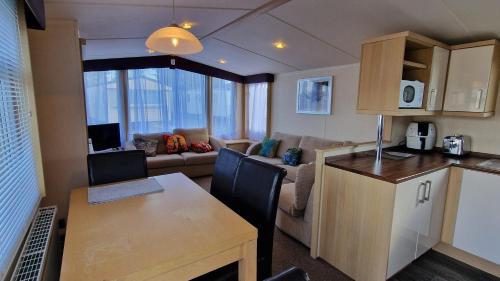 a kitchen and living room with a table and a couch at Oystercatcher Hide, Chruch Farm in Pagham