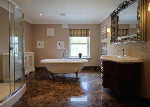 a bathroom with a tub and a sink and a mirror at Ballagh House in Navan
