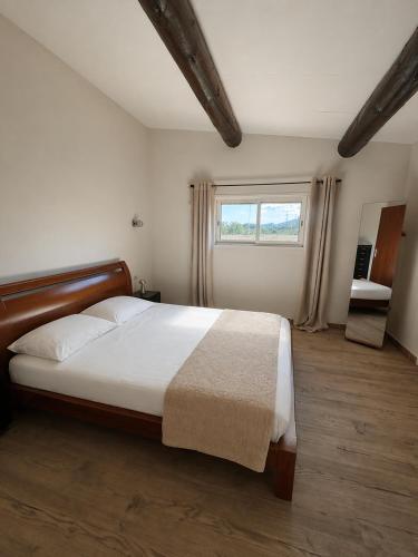 a bedroom with a large bed and a window at Mini Villa avec piscine privée in Porto-Vecchio