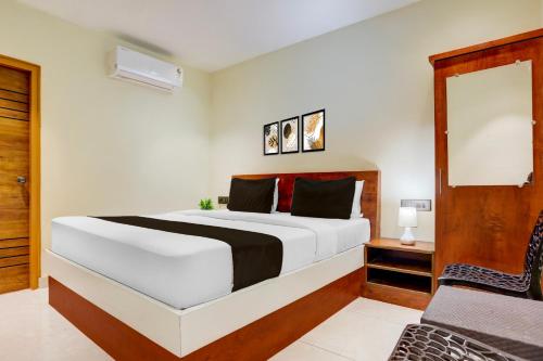 a bedroom with a large white bed and a chair at Super Hotel O Ananthpur Formerly TR Residency in Anantapur