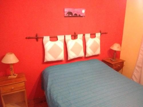a bedroom with a blue bed with red walls and two lamps at Cabañas Estrellas Doradas in Miramar