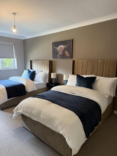 a bedroom with two beds with blue and white pillows at Waterside House in Kilbarchan