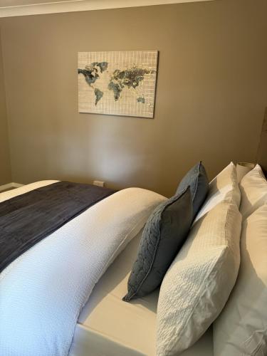 a bed with pillows and a map on the wall at Waterside House in Kilbarchan