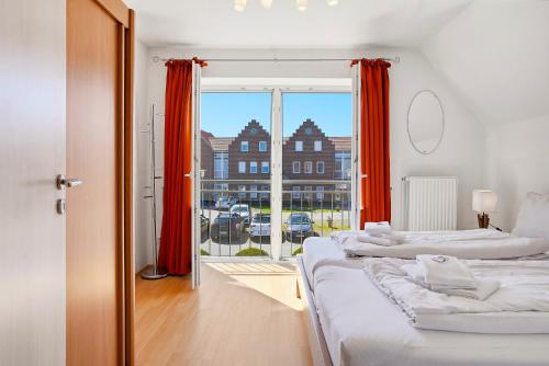 two beds in a room with a large window at Möwenblick in Norddeich