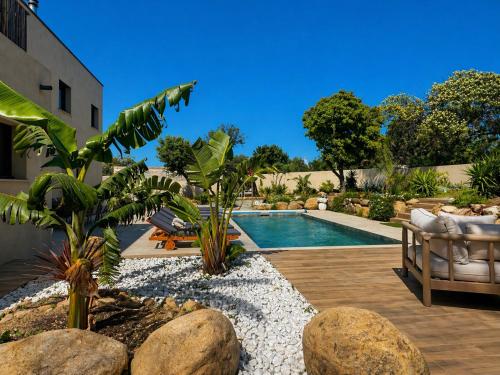 a swimming pool in a backyard with rocks and plants at Residence I Pozzi in Belgodère