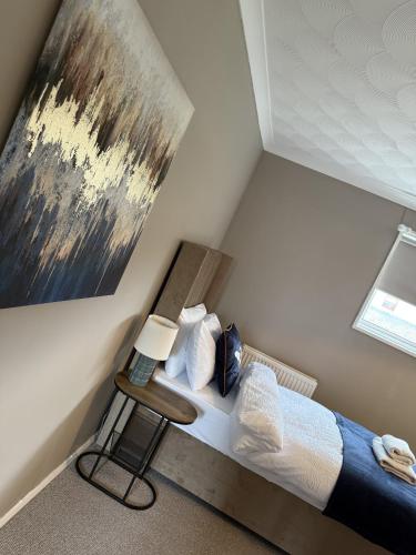 a bedroom with a bed and a painting on the wall at Knowes Apartment in Duntocher