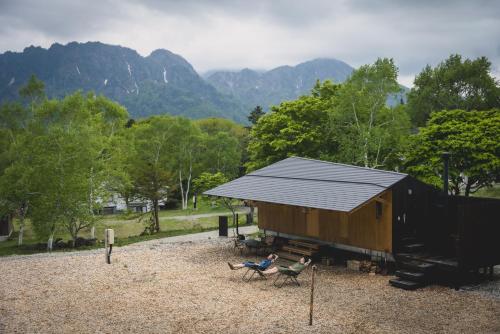 a person sitting in chairs in front of a cabin at Earthboat Togakushi in Nagano
