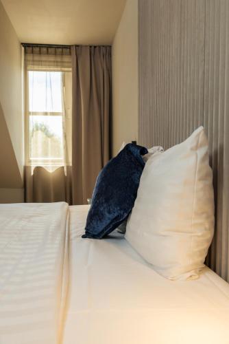 a white bed with a pillow and a window at Hotel Twenty-Three Amsterdam Airport in Hoofddorp