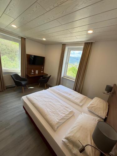 a bedroom with a large bed and two windows at BSW Ferienhotel Lindenbach in Bad Ems