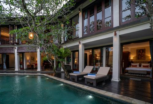 a villa with a swimming pool in front of a building at Villa Ambiente by Nakula in Jimbaran