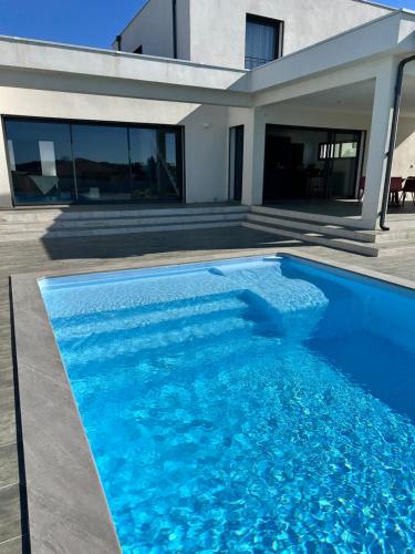 a swimming pool in front of a house at Spacieuse villa standing de 220m2 à 5 minutes des plages in Aléria