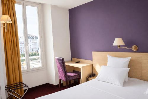 a hotel room with a bed and a desk and a window at Hôtel Continental in Lourdes