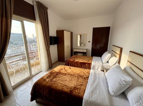 a hotel room with two beds and a large window at Ismailia House Inn in Cairo