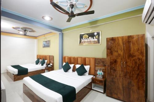 a bedroom with two beds and a ceiling fan at Hotel Radha Rani palace in Ayodhya