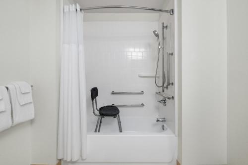 a black chair sitting in a shower in a bathroom at Garner Hotel Madison - Huntsville Airport by IHG in Madison
