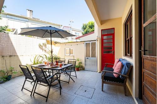 a patio with a table and chairs and an umbrella at Patio House - 2 Bedroom flat in Porto