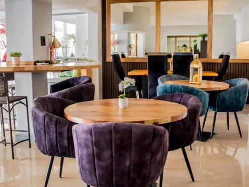 a restaurant with purple chairs and tables and a bottle of wine at San D- Lux Boutique Hotel in Durban