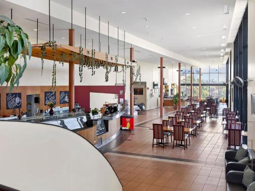 a cafeteria with a row of tables and chairs at BreakFree Wirrina Cove in Wirrina Cove