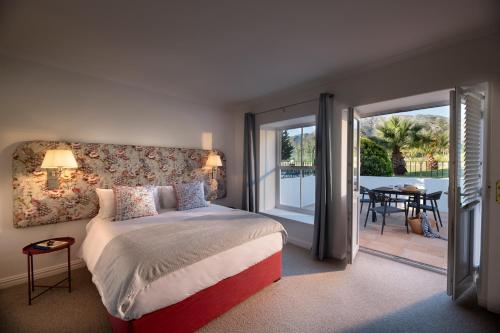 a bedroom with a bed and a sliding glass door at La Jolie Dauphine Guest House in Franschhoek