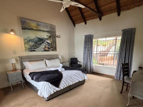 a bedroom with a bed with a ceiling fan and a window at Jimmy's Place in Dinokeng Game Reserve