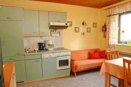 una cucina e un soggiorno con divano arancione di Ferienappartements mit Herz a Bischofsmais