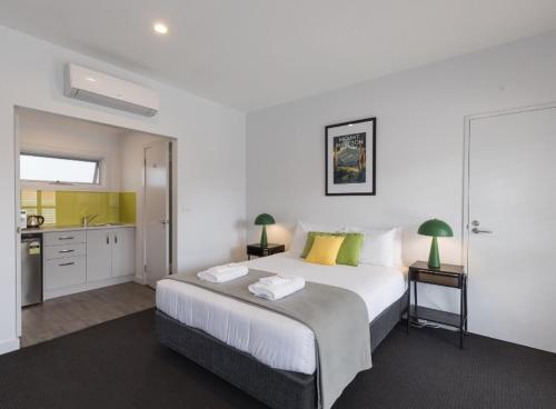 a bedroom with a large bed and a kitchen at The Dickins in Woodend
