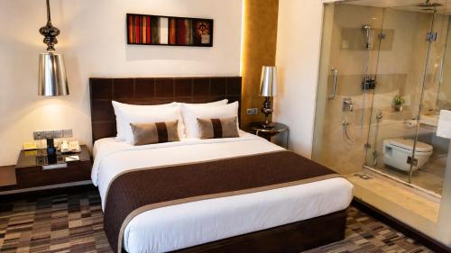 a bedroom with a large bed and a shower at Pride Premier Pune in Pune