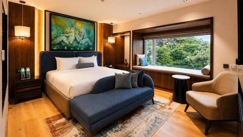 a bedroom with a bed and a chair and a window at Pride Premier Pune in Pune