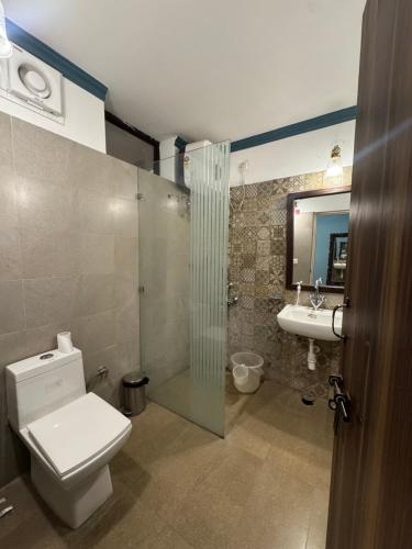 a bathroom with a toilet and a shower and a sink at Navya Niwas - The Rooms in Dehradun