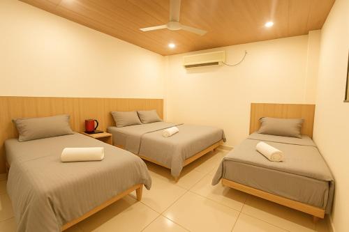 a bedroom with two beds and a fan at Hotel Avani Grand in Zahirābād