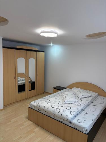 a bedroom with a large bed and a cabinet at Apartament Floare de Colț in Buşteni