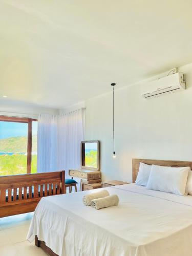 a bedroom with a white bed with two towels on it at Garden Hill Views in Kuta Lombok
