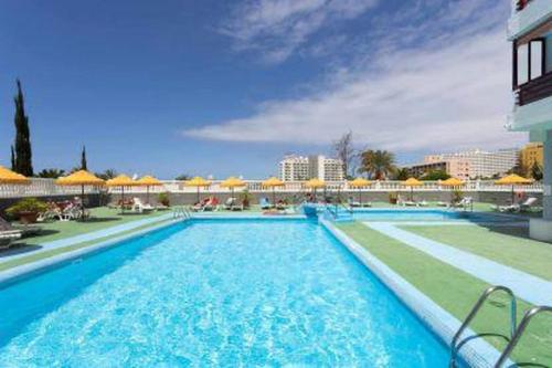 a large swimming pool with blue water in a resort at Eden Rentals Olympia Sunny Seaviews in Playa de las Americas