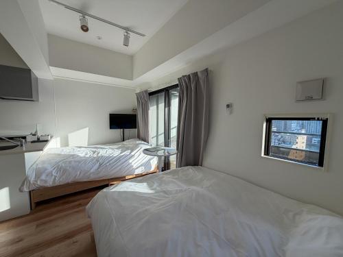 a bedroom with two beds and a window at KOTI Hakata in Fukuoka