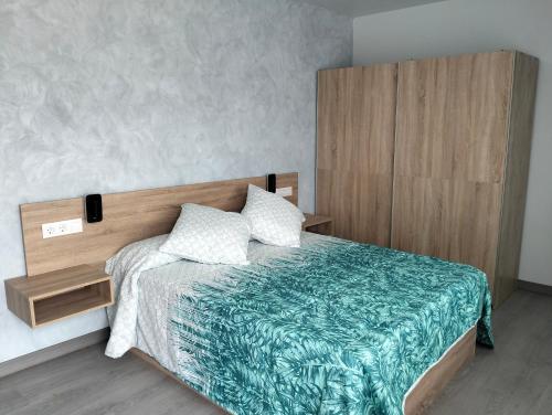 a bedroom with a bed with a wooden headboard at Casa Camiño dos Faros in Sinde