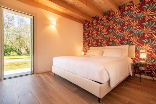 a bedroom with a bed and a large window at BORGO STALIS RESORT in Sesto al Reghena