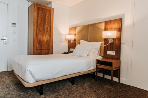 a bedroom with a large bed with a wooden headboard at Hotel Porto Downtown in Porto