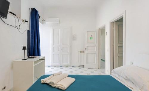 a white bedroom with a blue bed and a bathroom at Authentic Oasis - Villa La Solara in Anacapri