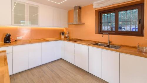 a kitchen with white cabinets and a window at Villa Infinity Torrox by Ruralidays in Torrox