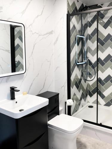 a bathroom with a sink and a toilet and a shower at Beyond Hotel & Apartments in Burnley