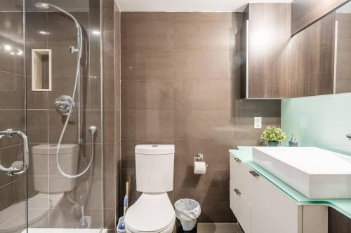 a bathroom with a shower and a toilet and a sink at Stylish 1BR plus Den Suite with Parking, Sleeps 4) in Toronto