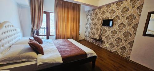 a bedroom with a bed and a tv on a wall at Karmia Boutique in Piatra Neamţ